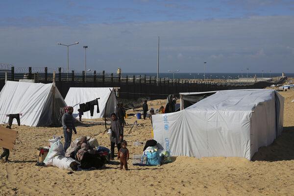 Palestinians displaced by the Israel air and ground offensive on the Gaza Striptake shelter near the border fence with Egypt in Rafah (Picture: AP Photo/Hatem Ali)